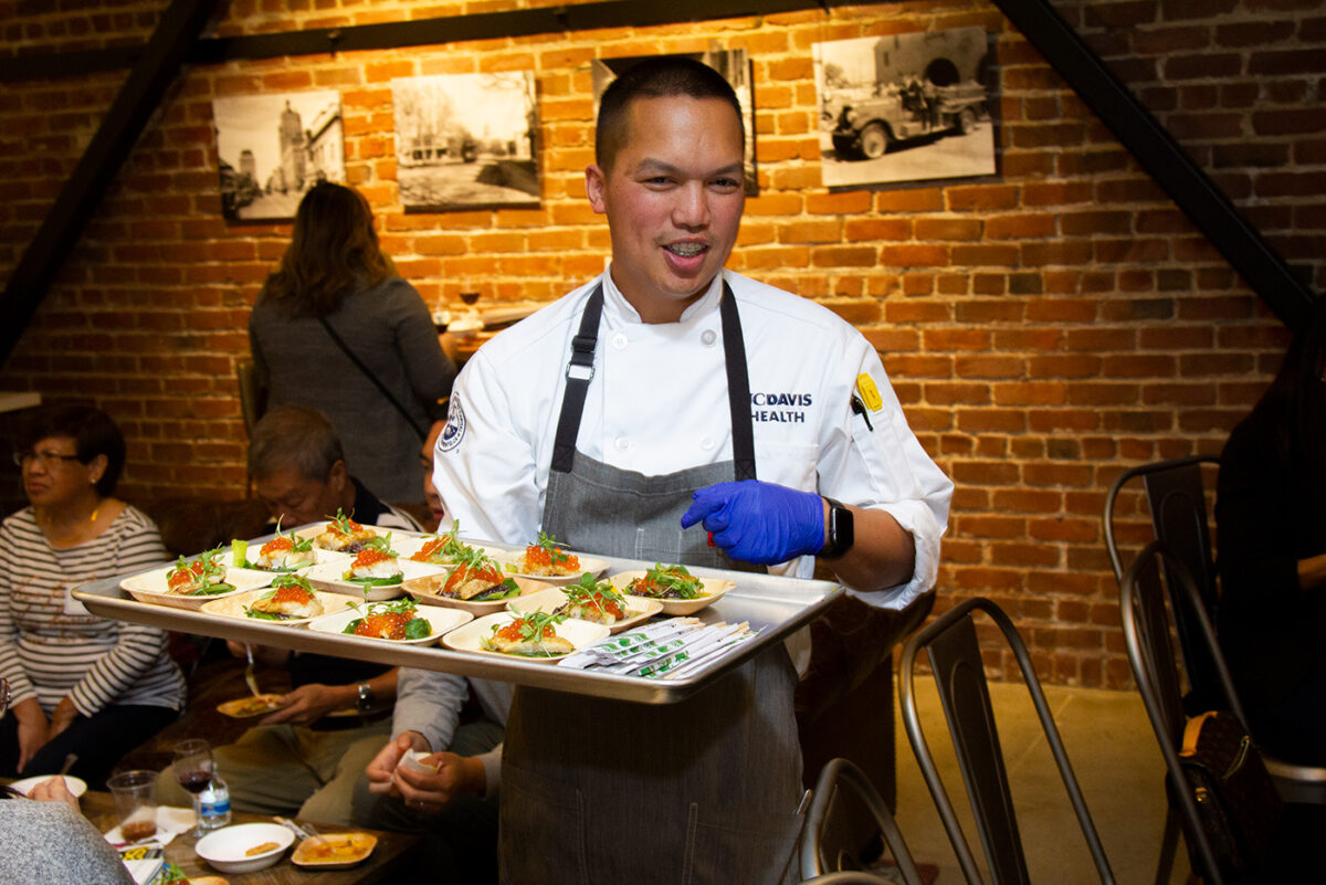 Jet Aguirre carries a tray of food during the AAJA Sacramento Chefs Showcase.